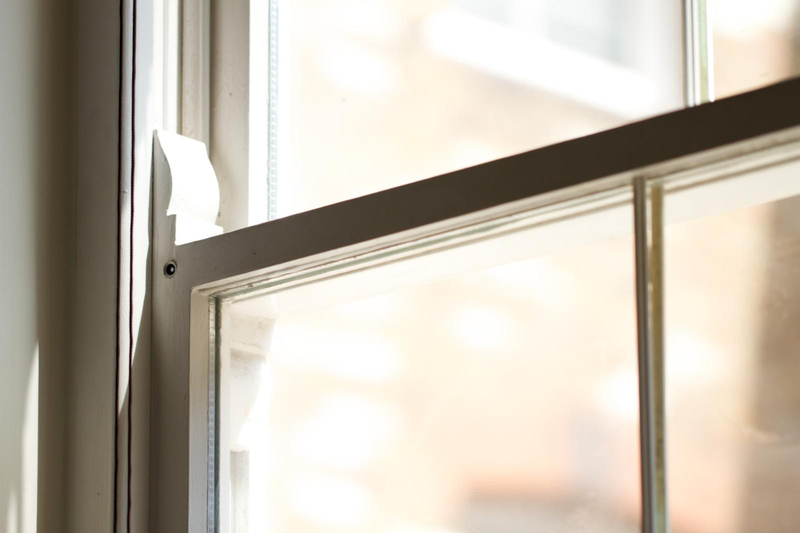 White window handle and locking mechanism on aluminium window frame with natural light filtering through