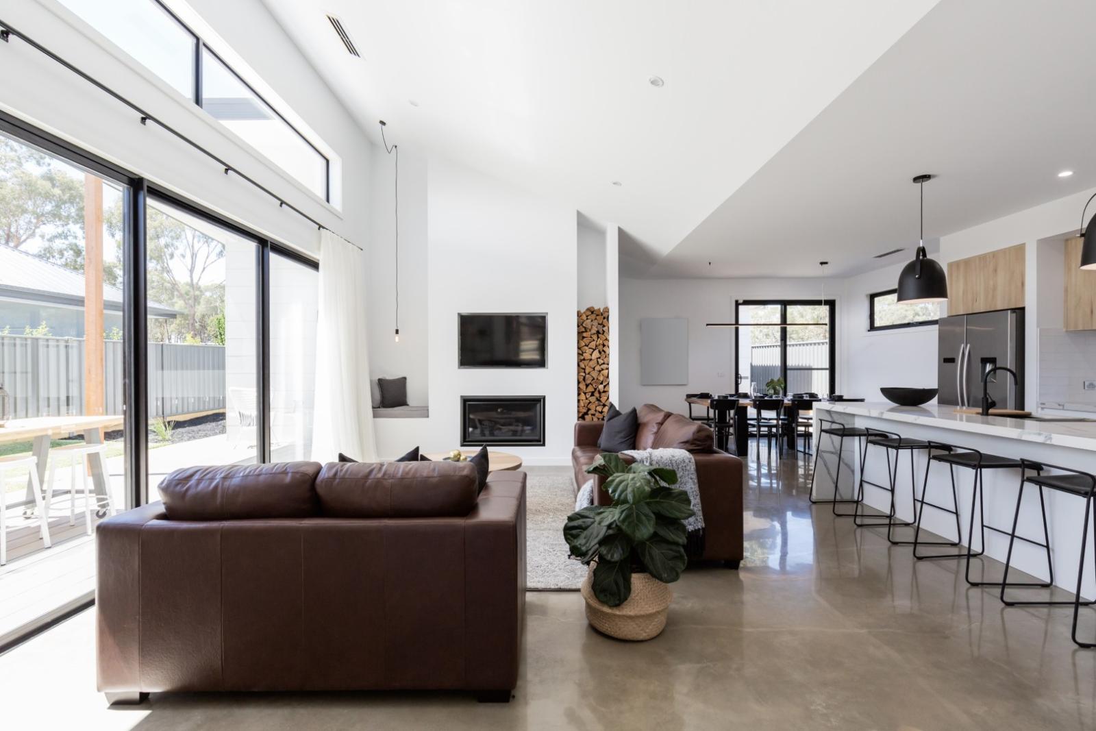 Modern open plan living space with large sliding windows, white frames, and contemporary interior design