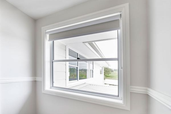 Modern awning window with white frame partially open showing outdoor view from interior room