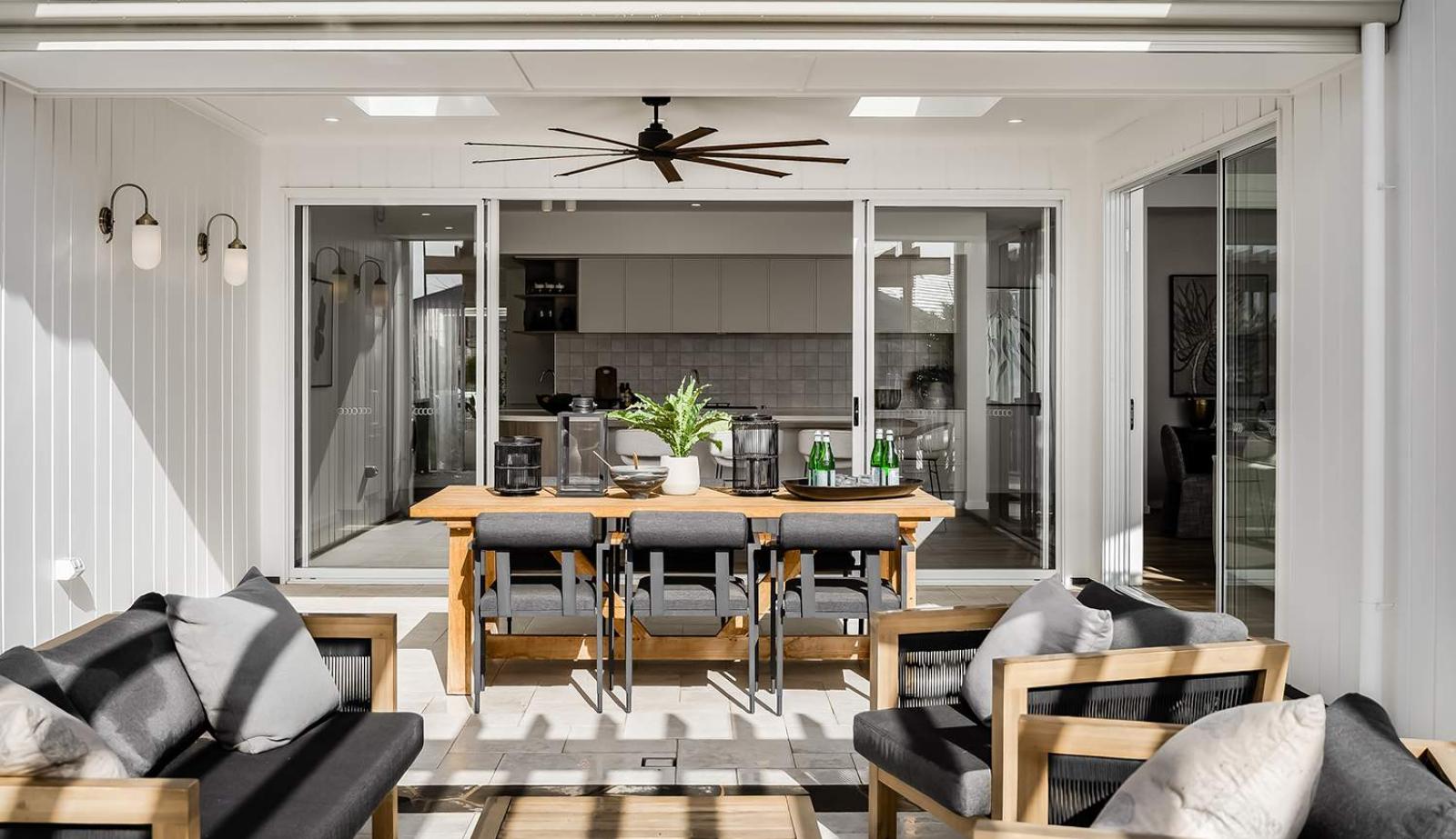 Modern sliding doors opening from living room to outdoor patio with dining area and BBQ